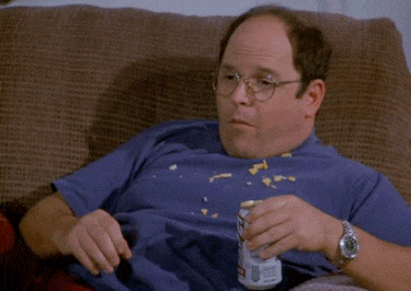 A gif of George from Seinfeld lounging on the couch, eating and holding a beer.
